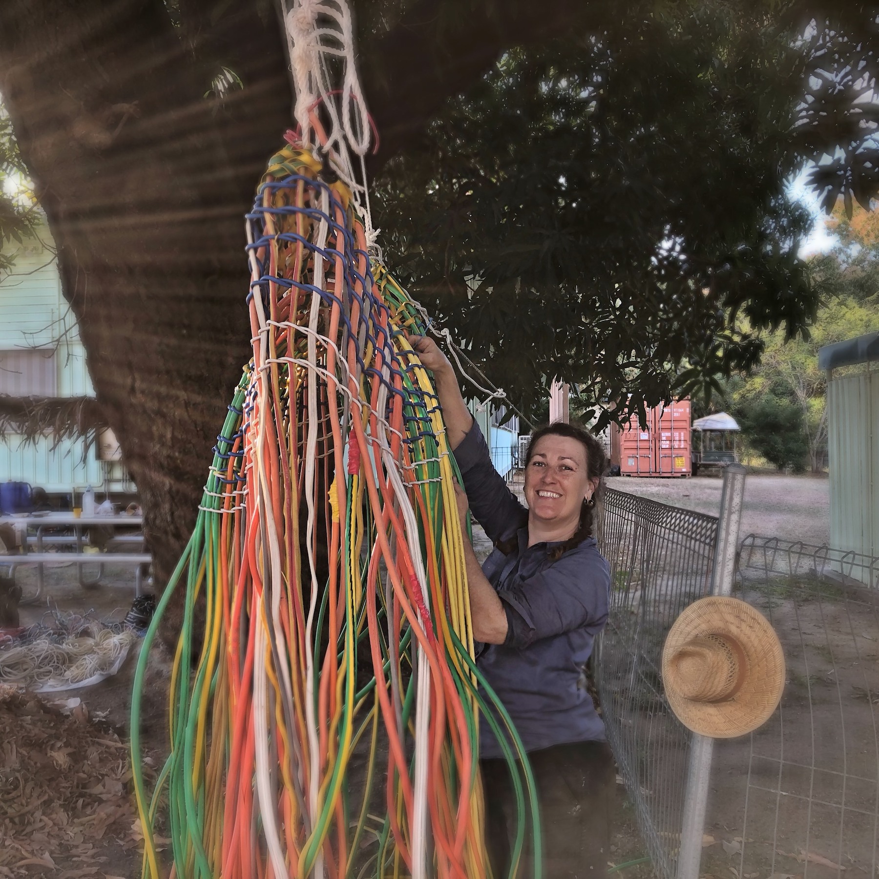 Bernadette works on weaving the big basket (Thawvl) under a mango tree in the community.